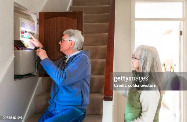 senior man checking electric fuses at home - fuse box stock pictures, royalty-free photos & images