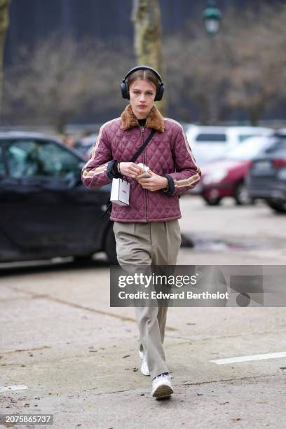 Model wears a burgundy quilted striped jacket, white sneakers, grey pants outside Chanel, during the Womenswear Fall/Winter 2024/2025 as part of...