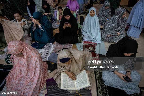 An Indonesian muslim woman read Qur'an as they attend Tarawih prayers to mark the start of the holy month of Ramadan at UGM Campus Mosque on March...