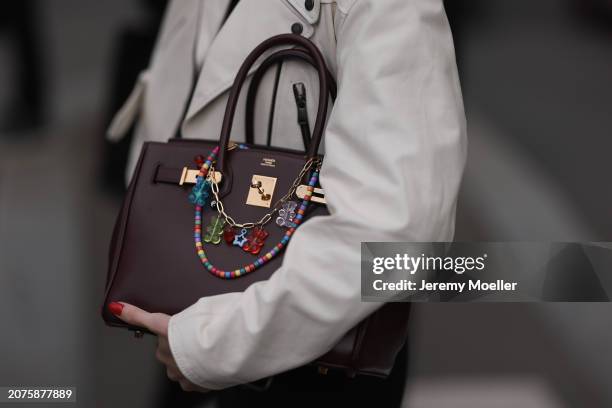 Guest seen wearing a white leather short trenchcoat jacket and a winered Hermès birkin bag with colourful bag chains outside Miu Miu Show during the...