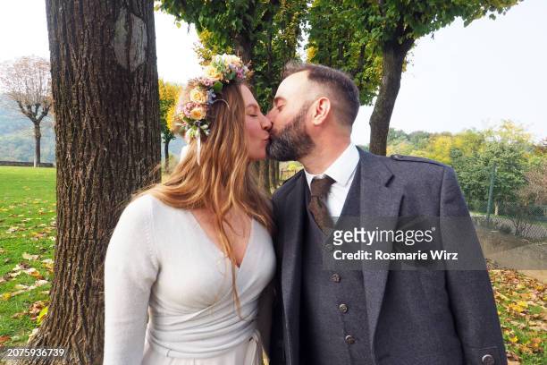 bride and groom kissing, waist up, autumn parkland - ambivere stock pictures, royalty-free photos & images
