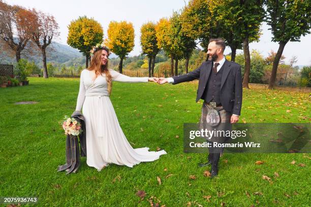 bride and groom holding hands, autumn parkland - ambivere stock pictures, royalty-free photos & images