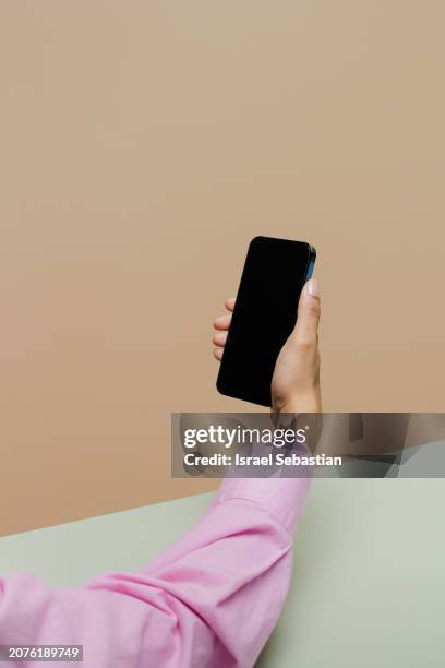 anonymous latina woman with smartphone in hand on green and brown background. - smartphone text message screen stock-fotos und bilder