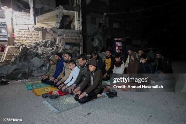 March 11: Palestinian citizens perform Tarawih prayers on the first day of the holy month of Ramadan on the rubble of Al-Huda Mosque, which was...