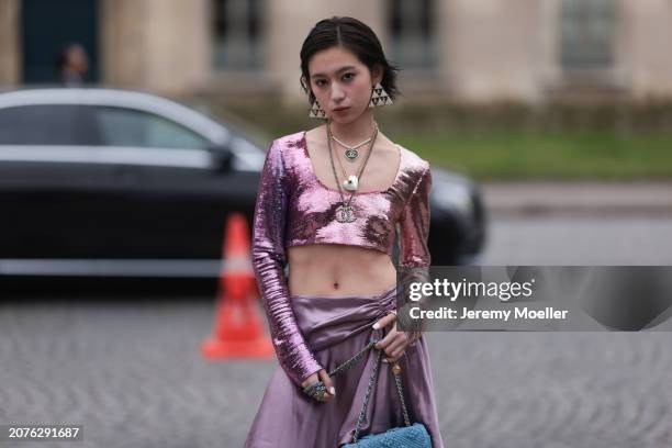 Fashion Week Guest seen wearing a rose shimmery cropped shirt, purple skirt, Chanel blue handbag, Chanel triangle earrings, silver pearls necklace...