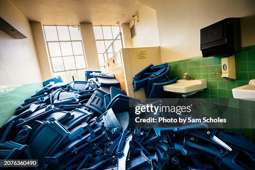 Broken chairs in a bathroom inside an abandoned school