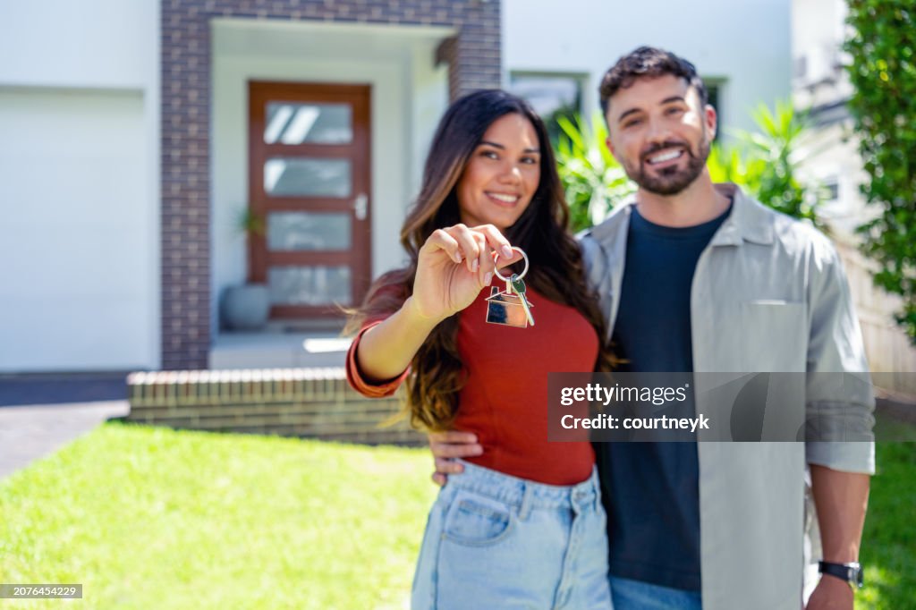 Happy woman and man, holding keys from new first house, young family celebrating moving day,