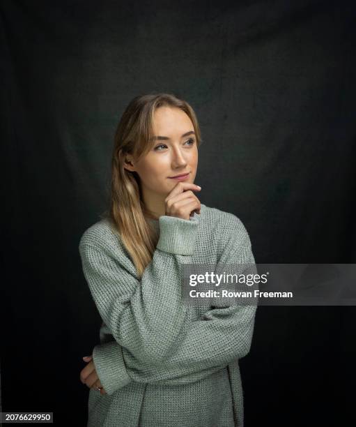 young woman in casual sweater with hand on chin - sourire narquois photos et images de collection