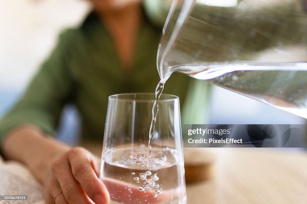 Woman Pouring Water From Jug Into Glass