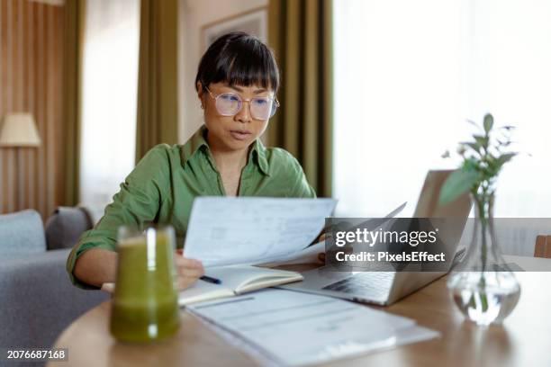 donna d'affari che controlla il rapporto sui dati finanziari presso l'ufficio di casa - tasse foto e immagini stock