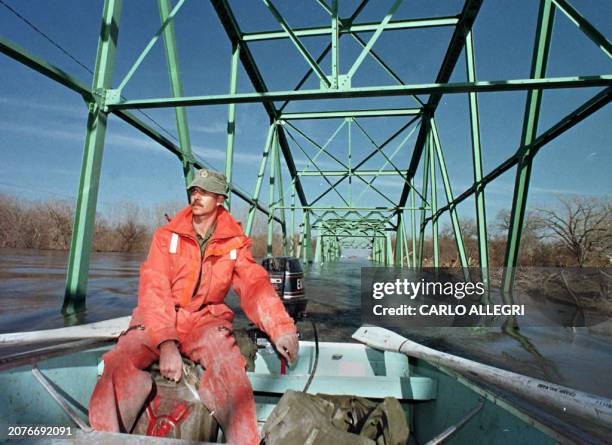 Canadian Military Master Sgt. Joe Bisson drives his boat across a bridge over a road that the Red River is flowing over in St. Jean Baptise, Canada,...