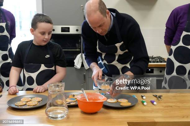 Prince William, Prince Of Wales decorates biscuits with the help of young people during his visit to WEST, a new OnSide Youth Zone WEST on March 14,...