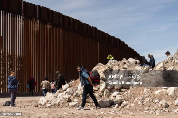 Group of asylum seekers rest along the border wall during their 19 mile walk to Sasabe, Arizona, US, on Wednesday, March 13, 2024. During the first...