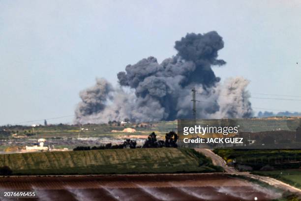 An agricultural field is irrigated in southern Israel as smoke billows over the Gaza Strip during Israeli bombardment on March 14 amid the ongoing...