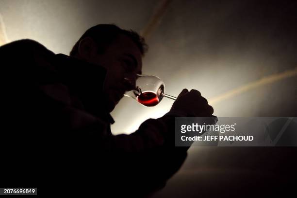 Man tastes wine in the "Nouvelle cuverie" of the Hospices de Beaune prior to their 150th charity auction wine sale, on November 21, 2010 in Beaune,...