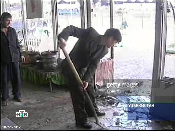 Grab from Russian channel NTV shows a worker cleaning broken glass 29 March 2004 from the blast site at the market place in the Uzbek capital of...