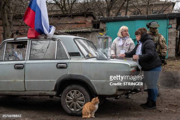 Members of a local election commission, accompanied by a serviceman, prepare a mobile polling station during early voting in Russia's presidential...