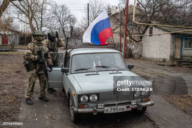 Members of a local election commission, accompanied by servicemen, visit voters during early voting in Russia's presidential election in Donetsk,...