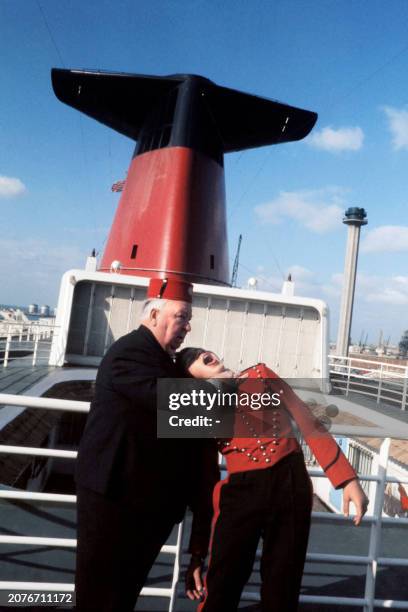 British film director Alfred Hitchcock jokes with a groom on board The French prestigious ocean liner France, on October 20, 1972 in Le Havre, before...