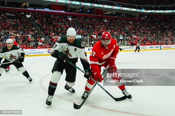 David Perron of the Detroit Red Wings fights for position with Lawson Crouse of the Arizona Coyotes during the first period at Little Caesars Arena...