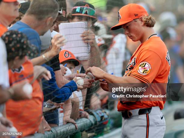 Jackson Holliday of the Baltimore Orioles signs autographs for fans prior to the start of a spring training game against the Pittsburgh Pirates at...