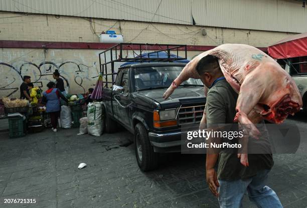 Man delivers raw, unwrapped pork to a local butcher shop in Old Town Puebla, on December 7 in Puebla, Puebla State, Mexico.