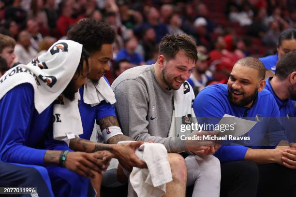 Derrick Jones Jr. #55, P.J. Washington and Luka Doncic of the Dallas Mavericks laugh on the bench against the Chicago Bulls during the second half at...