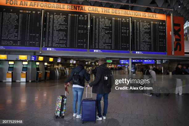 Passengers stand in front of an announcement board in Terminal 1 showing cancelled Lufthansa flights during a flight attendant protest at Frankfurt...