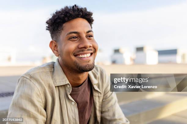 portrait of young smiling african american man sitting outdoors. - männer stock-fotos und bilder