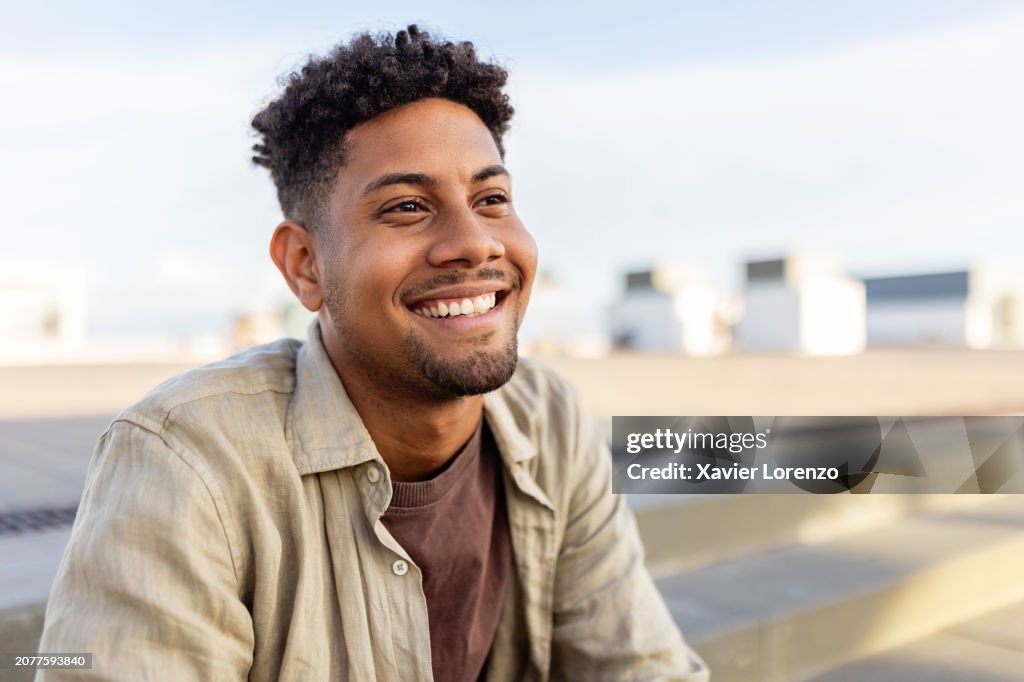 Portrait of young smiling african american man sitting outdoors.