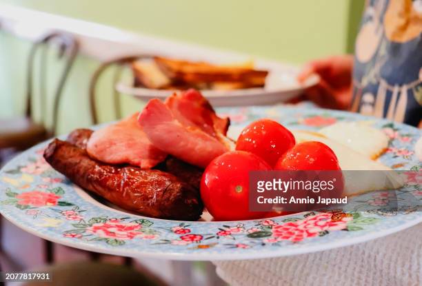 server holding breakfast plate with sausages, bacon, eggs and cherry tomatoes - galway people stock pictures, royalty-free photos & images