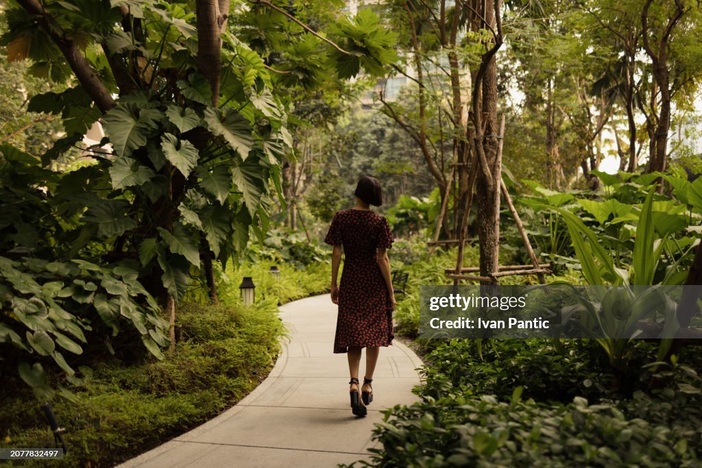 Back view of carefree woman taking a walk in the park.