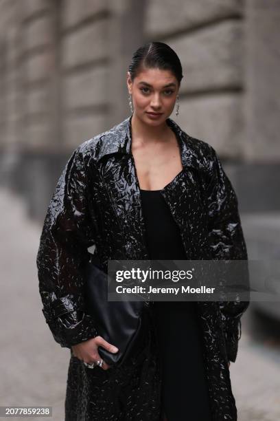 Sarah Posch seen wearing Pilgrim silver earrings, H&M black cotton jumpsuit, Boss black shiny varnished leather oversized long coat, Calvin Klein...