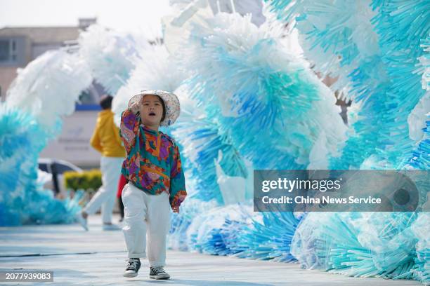 Child plays among 'sea wave' art installation made of tens of thousands of environmentally-friendly straws at a shopping center on March 12, 2024 in...