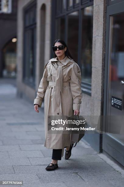 Tugba Kement seen wearing YSL black sunglasses, COS beige oversized long coat, black long suit pants, Hermès Kelly taupe / brown leather bag, gold...
