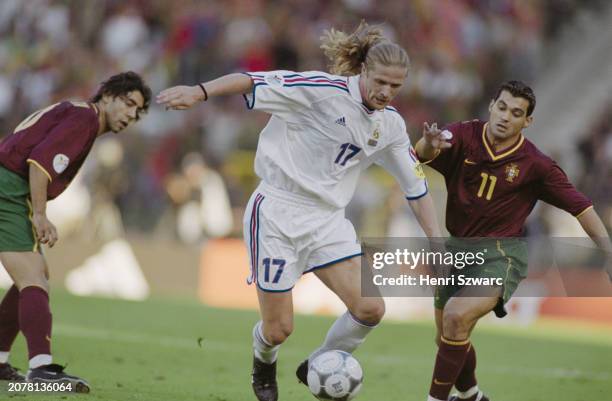 Portugal footballer Rui Costa watches France footballer Emmanuel Petit and Portugal footballer Sergio Conceicao vie for possession during the UEFA...