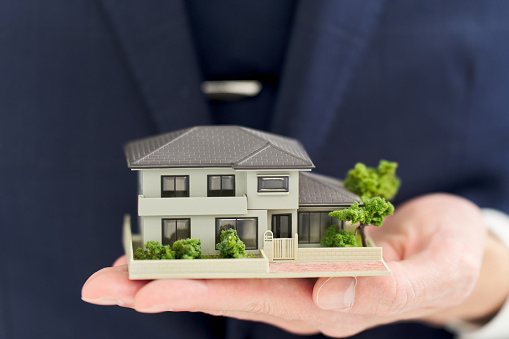 Hand of a businessman holding a model of a house