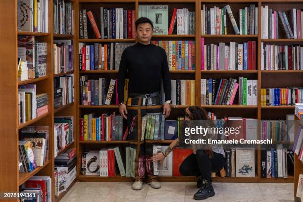 An assistant paints some details of the camouflage of Chinese artist Liu Bolin as he prepares to perform at Libreria Hoepli on March 12, 2024 in...