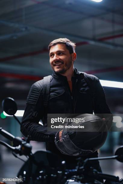 portrait of a handsome smiling man on a motorcycle holding a helmet - motorcycle biker stock pictures, royalty-free photos & images