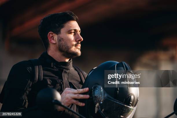 retrato de un motociclista en su bicicleta sosteniendo un casco - guy motorbike fotografías e imágenes de stock