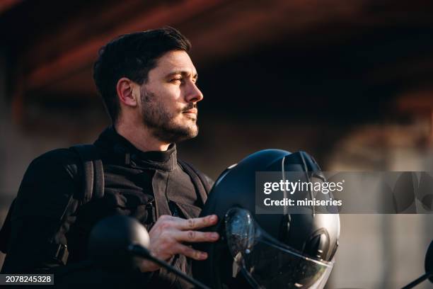 retrato de un motociclista en su bicicleta sosteniendo un casco - sports helmet fotografías e imágenes de stock