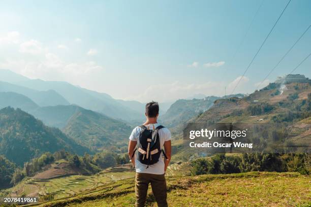 rear view of young asian man looking at view among terraced rice fields in the mountain - north vietnam stock pictures, royalty-free photos & images