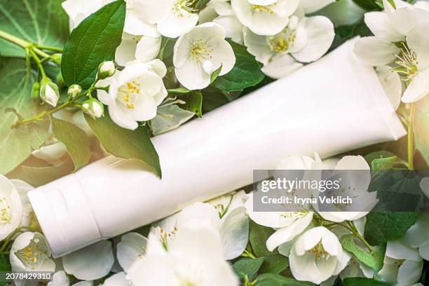 natural beauty cosmetic product in white plastic tube skin care face cream, hand cream, suntan lotion, shampoo for skin care on white and green bokeh jasmine flowers background. sunlight with bokeh. - creme tube ストックフォトと画像
