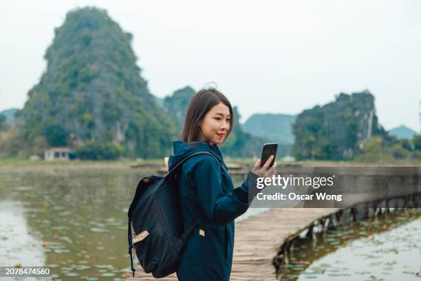 young asia woman using smartphone while exploring the nature in vietnam - vietnam mobile phone photos et images de collection