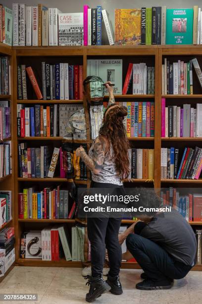 Two assistants paint some details of the camouflage of Chinese artist Liu Bolin as he prepares to perform at Libreria Hoepli on March 12, 2024 in...