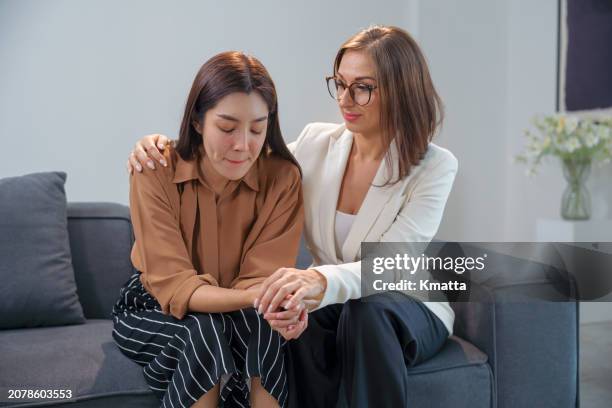 female therapist giving support to a female patient with hand on her shoulder during therapy session. woman getting psychological support during privacy therapy session. - encouragement stock pictures, royalty-free photos & images