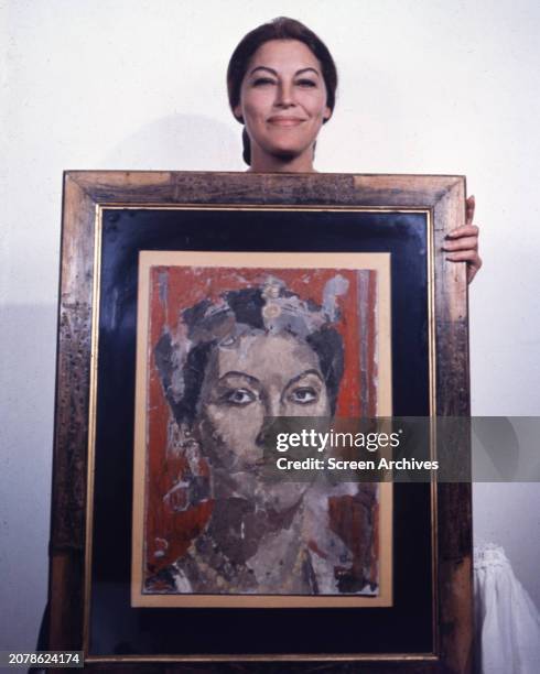 Ava Gardner posing with painting of herself, circa 1964.