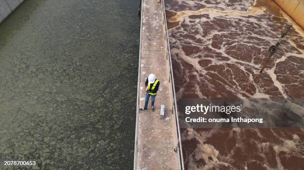 drone view of environmental specialist walking through and work inspecting water treatment pond - estação de tratamento de esgotos imagens e fotografias de stock