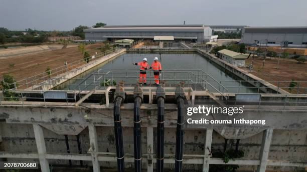 aerial view shot of two diverse environmentalists working on the sunlight at a wastewater treatment plant in the industrial estate by walking around and checking the quality of the water - pollution prevention stock pictures, royalty-free photos & images