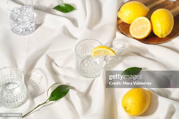 silk wavy white cloth with cocktail glasses and lemons - lemon party picture stockfoto's en -beelden